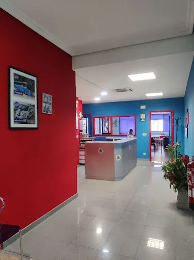 Recepción de la sede de A Cañiza, con mostrador y cuadros de coches sobre pared roja