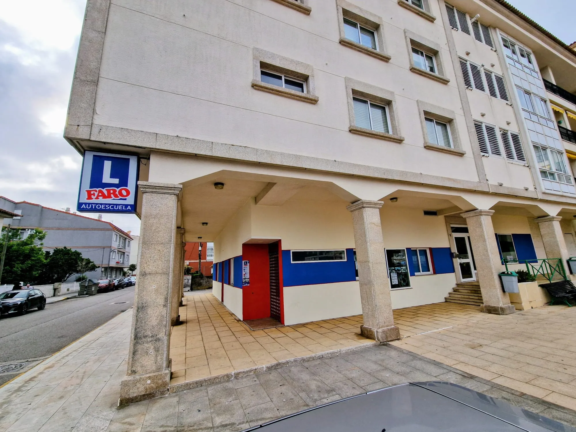 Entrada de la sede de Panxón, con soportal de columnas de piedra y el cartel de Faro Autoescuela