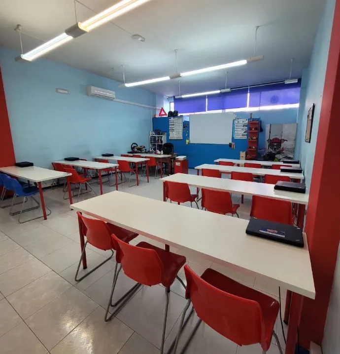 Aula teórica de la sede de Plaza América en Vigo, con pizarra, señales de tráfico y puestos para alumnos